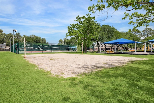 view of community featuring volleyball court, fence, and a yard
