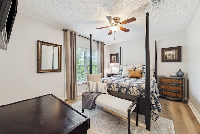 bedroom featuring a textured ceiling, light wood-style floors, ceiling fan, baseboards, and visible vents