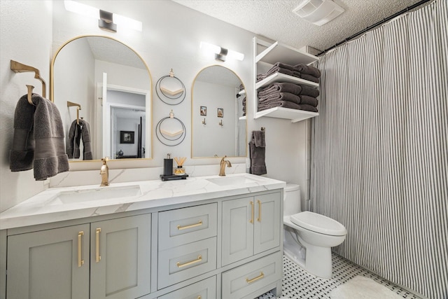 bathroom with toilet, a sink, double vanity, and a textured ceiling