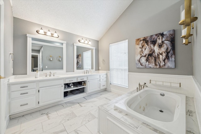 full bath featuring lofted ceiling, wainscoting, marble finish floor, and a sink