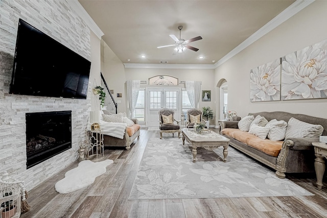 living room with arched walkways, wood finished floors, ceiling fan, and ornamental molding