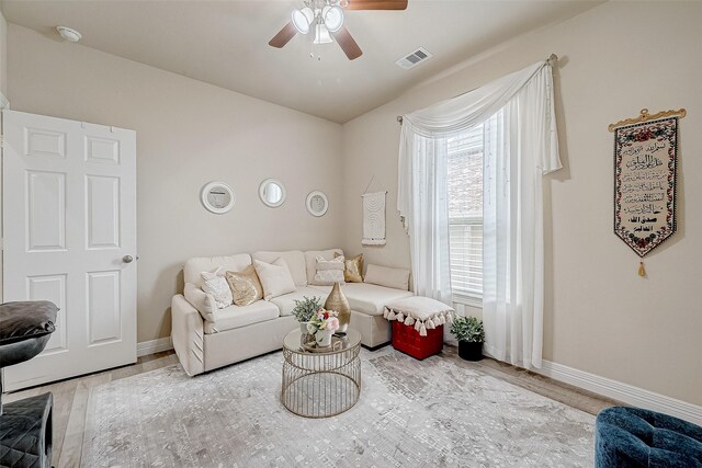 living area featuring visible vents, baseboards, wood finished floors, and ceiling fan