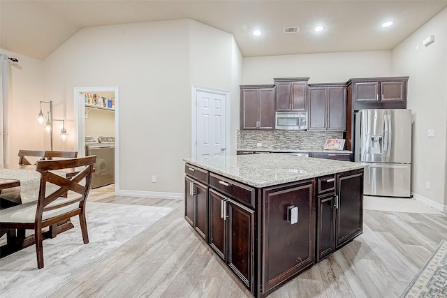 kitchen with tasteful backsplash, visible vents, washer and clothes dryer, stainless steel appliances, and light wood finished floors