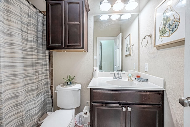 bathroom featuring toilet, vanity, and a textured wall