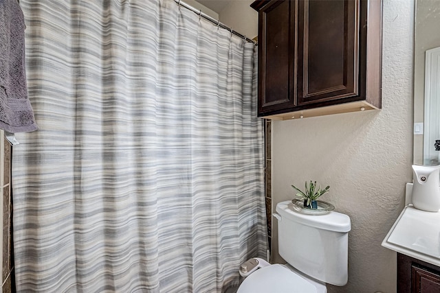 full bathroom featuring toilet, a shower with curtain, vanity, and a textured wall