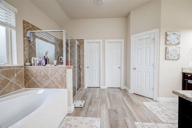 bathroom featuring vanity, baseboards, a stall shower, a bath, and wood finished floors