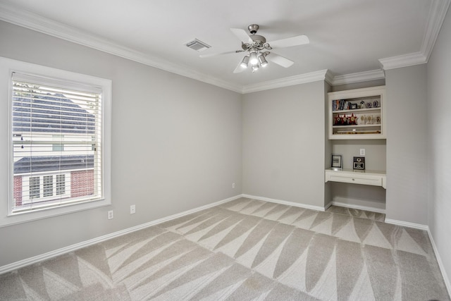 unfurnished room with built in study area, visible vents, ornamental molding, baseboards, and light colored carpet