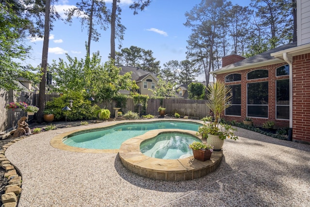 view of pool with a fenced backyard and an in ground hot tub