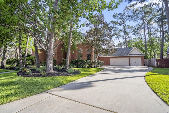 traditional-style home featuring a front lawn, driveway, fence, brick siding, and an attached garage