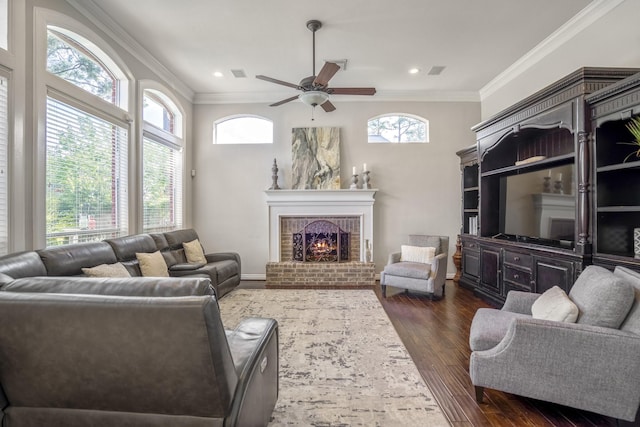 living room featuring ornamental molding, a ceiling fan, a brick fireplace, and dark wood-style floors