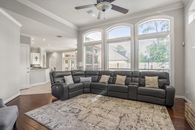living room featuring a ceiling fan, visible vents, and crown molding