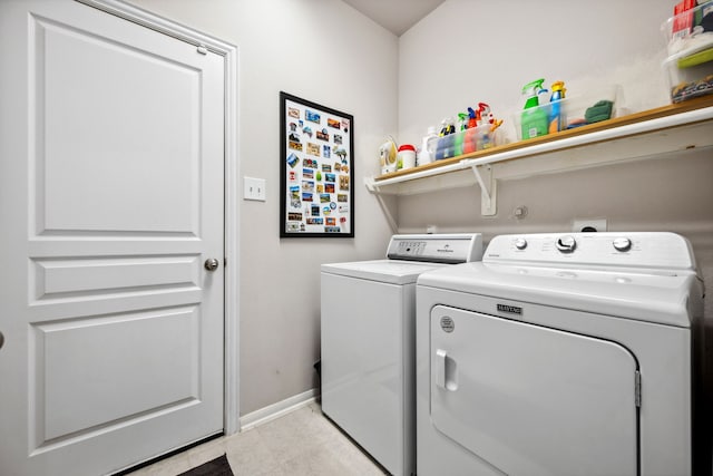 clothes washing area with light tile patterned floors, baseboards, washer and dryer, and laundry area