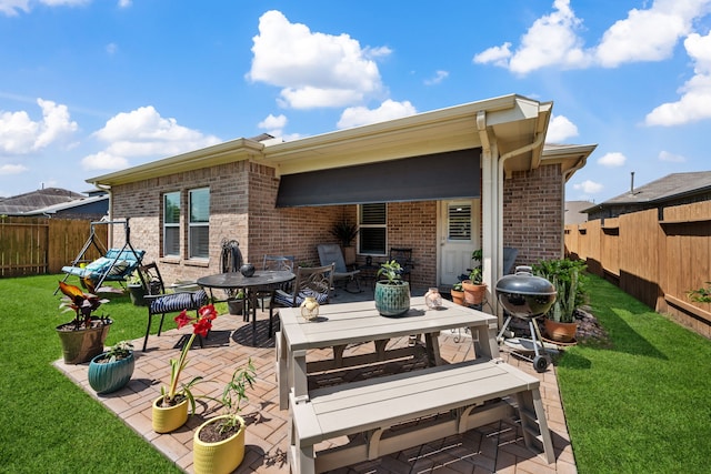 back of house featuring outdoor dining area, brick siding, a patio area, and a fenced backyard