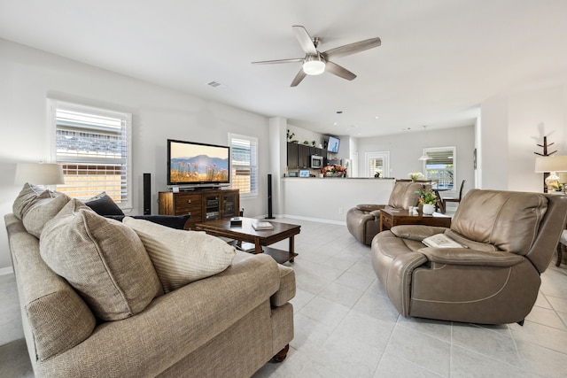 living area featuring visible vents, baseboards, ceiling fan, and light tile patterned floors