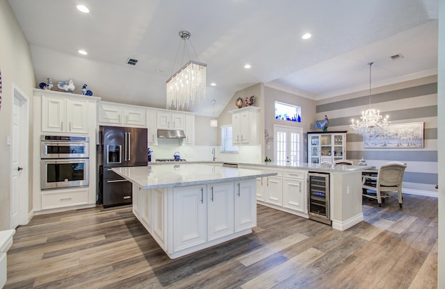 kitchen featuring a notable chandelier, a peninsula, under cabinet range hood, wine cooler, and stainless steel appliances