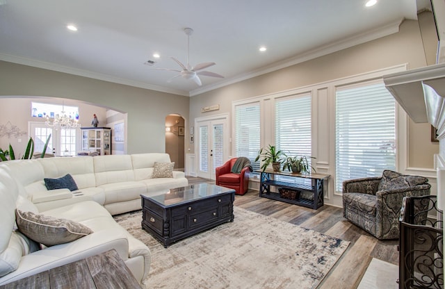 living room featuring recessed lighting, crown molding, arched walkways, ceiling fan with notable chandelier, and wood finished floors
