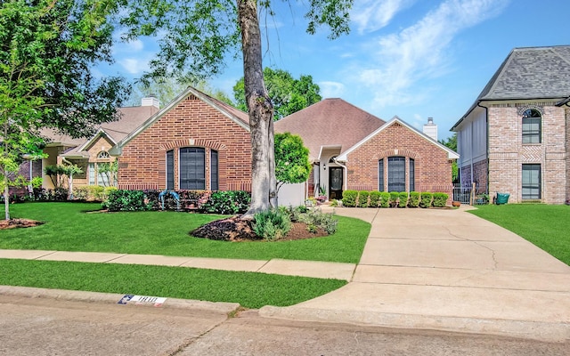 view of front of property with a chimney, brick siding, and a front yard