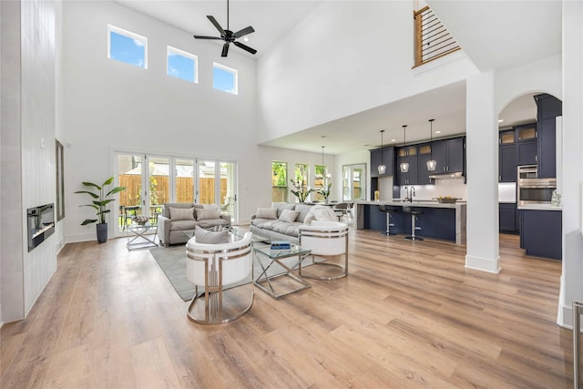 3314 Arbor, Houston, TX 77004 - living room with a ceiling fan, arched walkways, a towering ceiling, light wood-type flooring, and baseboards
