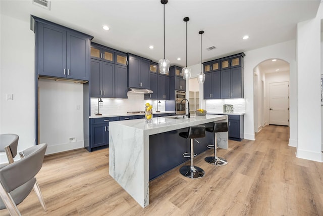 3314 Arbor, Houston, TX 77004 - kitchen with arched walkways, decorative backsplash, a kitchen bar, a sink, and light stone countertops