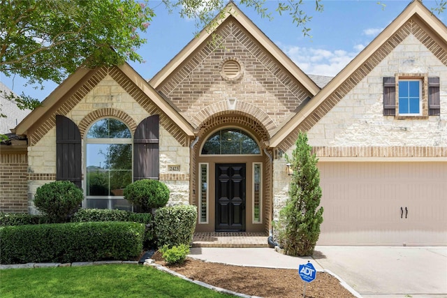 2423 Rosillos Peak Dr, Spring, TX 77386 - view of exterior entry with stone siding, an attached garage, driveway, and brick siding