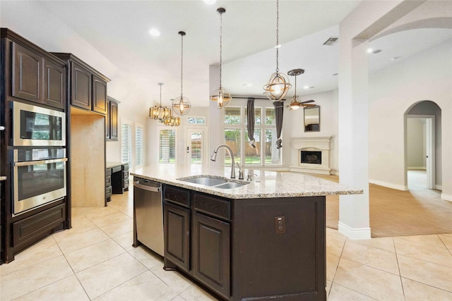 2423 Rosillos Peak Dr, Spring, TX 77386 - kitchen featuring appliances with stainless steel finishes, arched walkways, a sink, light tile patterned floors, and dark brown cabinets