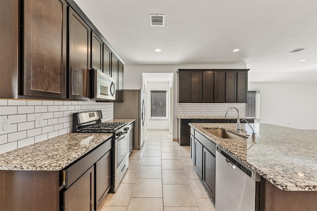 29607 Ella Larchmont Ct, Katy, TX 77494 - kitchen with visible vents, appliances with stainless steel finishes, light stone counters, a sink, and decorative backsplash