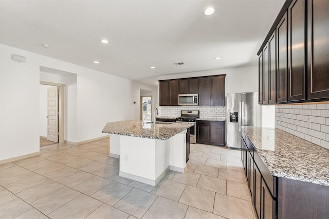 29607 Ella Larchmont Ct, Katy, TX 77494 - kitchen featuring appliances with stainless steel finishes, light tile patterned flooring, a sink, light stone counters, and decorative backsplash