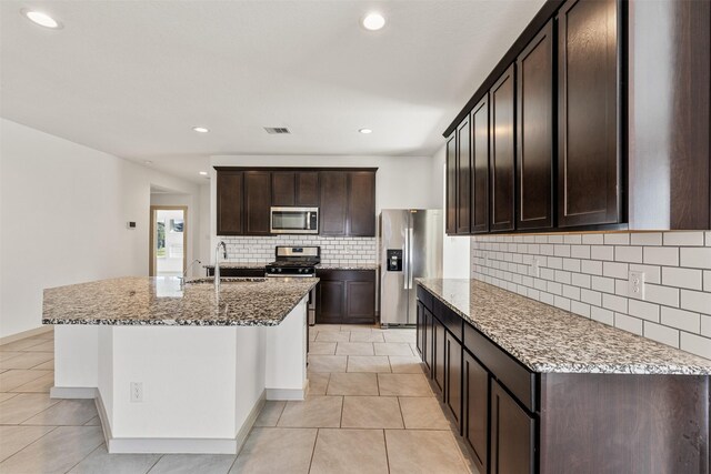 29607 Ella Larchmont Ct, Katy, TX 77494 - kitchen with tasteful backsplash, light stone countertops, visible vents, appliances with stainless steel finishes, and a sink