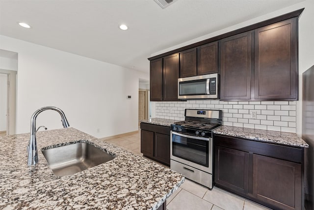 29607 Ella Larchmont Ct, Katy, TX 77494 - kitchen with light tile patterned floors, a sink, light stone countertops, decorative backsplash, and stainless steel appliances