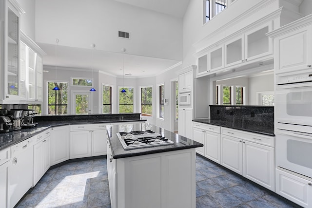 kitchen with visible vents, a peninsula, white appliances, and stone tile floors