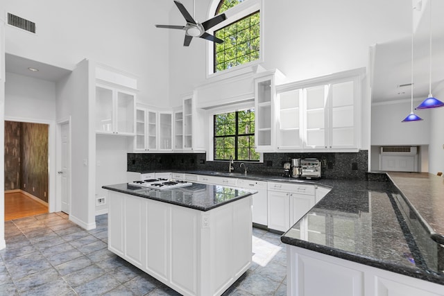 kitchen with visible vents, a high ceiling, a sink, ceiling fan, and white gas stovetop
