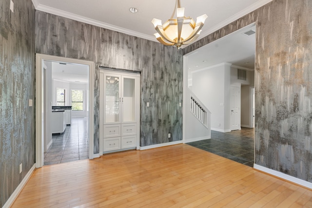 spare room featuring a chandelier, hardwood / wood-style floors, visible vents, and stairs