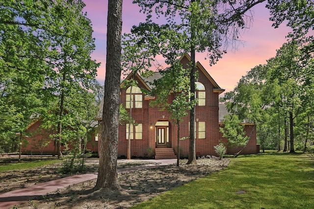 view of front facade featuring brick siding and a lawn