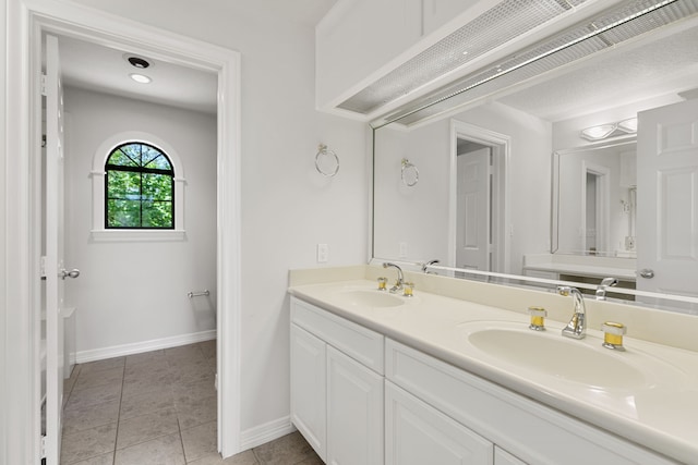 full bathroom with tile patterned flooring, double vanity, baseboards, and a sink