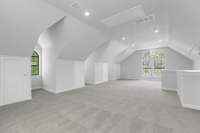 additional living space featuring plenty of natural light, visible vents, attic access, and lofted ceiling