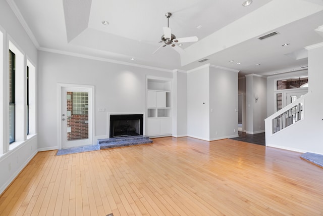 unfurnished living room featuring visible vents, built in shelves, a ceiling fan, crown molding, and light wood finished floors