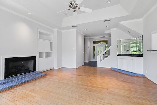 unfurnished living room featuring built in shelves, visible vents, ceiling fan, and light wood finished floors