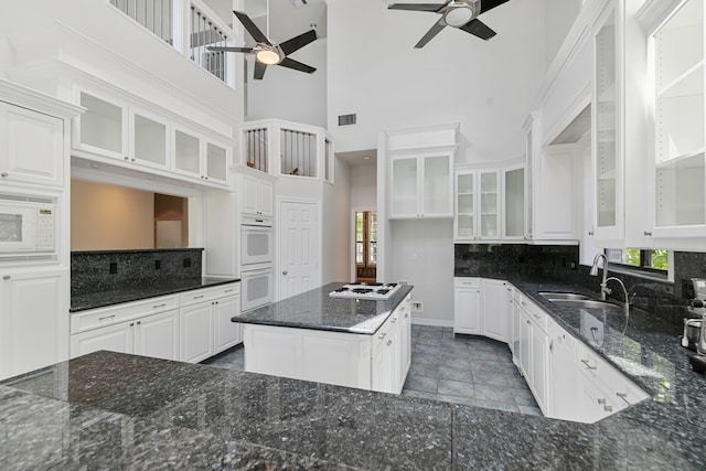 kitchen featuring visible vents, a sink, a ceiling fan, white appliances, and backsplash