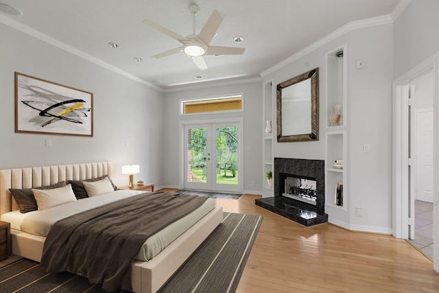 bedroom featuring a premium fireplace, crown molding, access to exterior, and light wood-style floors
