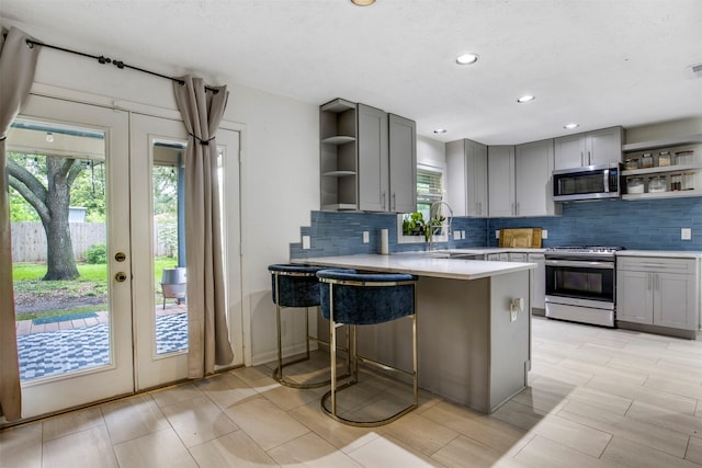3703 Peppermill Rd, Houston, TX 77080 - kitchen with open shelves, stainless steel appliances, gray cabinets, decorative backsplash, and recessed lighting