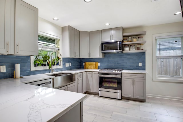 3703 Peppermill Rd, Houston, TX 77080 - kitchen featuring appliances with stainless steel finishes, gray cabinetry, tasteful backsplash, light stone countertops, and a sink