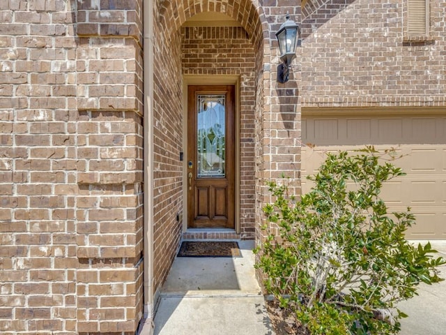 property entrance with a garage and brick siding
