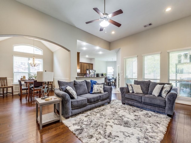 living area featuring ceiling fan with notable chandelier, dark wood finished floors, arched walkways, visible vents, and recessed lighting