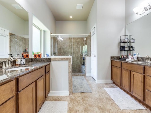 full bath with a sink, tile patterned flooring, two vanities, and a stall shower