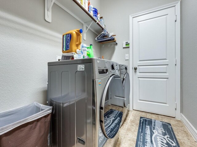 laundry area with washer and clothes dryer, tile patterned flooring, and laundry area