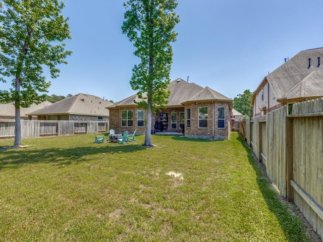 back of house with brick siding, a fenced backyard, and a lawn