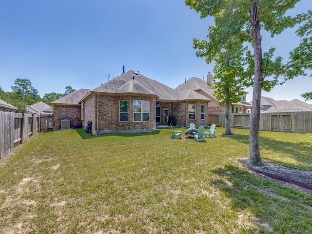 back of property with a fire pit, brick siding, a fenced backyard, a yard, and a shingled roof