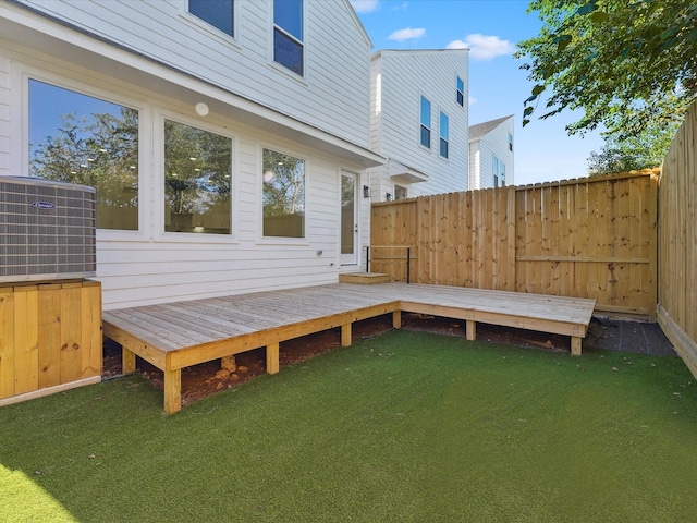 wooden deck with a yard, cooling unit, and fence