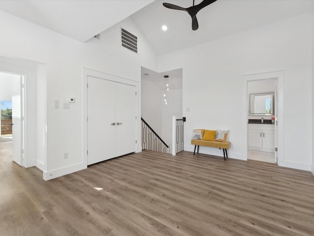 unfurnished living room featuring visible vents, baseboards, ceiling fan, light wood finished floors, and high vaulted ceiling