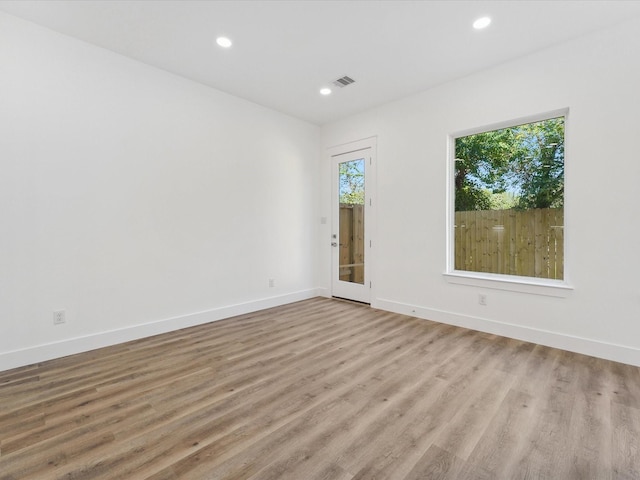empty room with visible vents, baseboards, light wood-type flooring, and recessed lighting